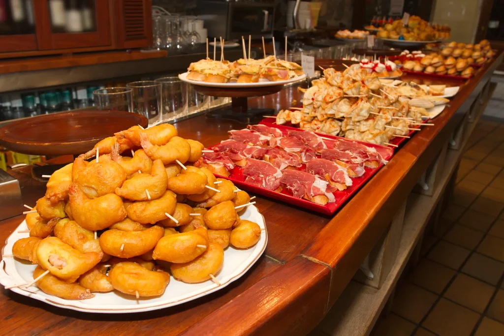 Bandejas de tapas variadas expuestas sobre la barra de un bar
