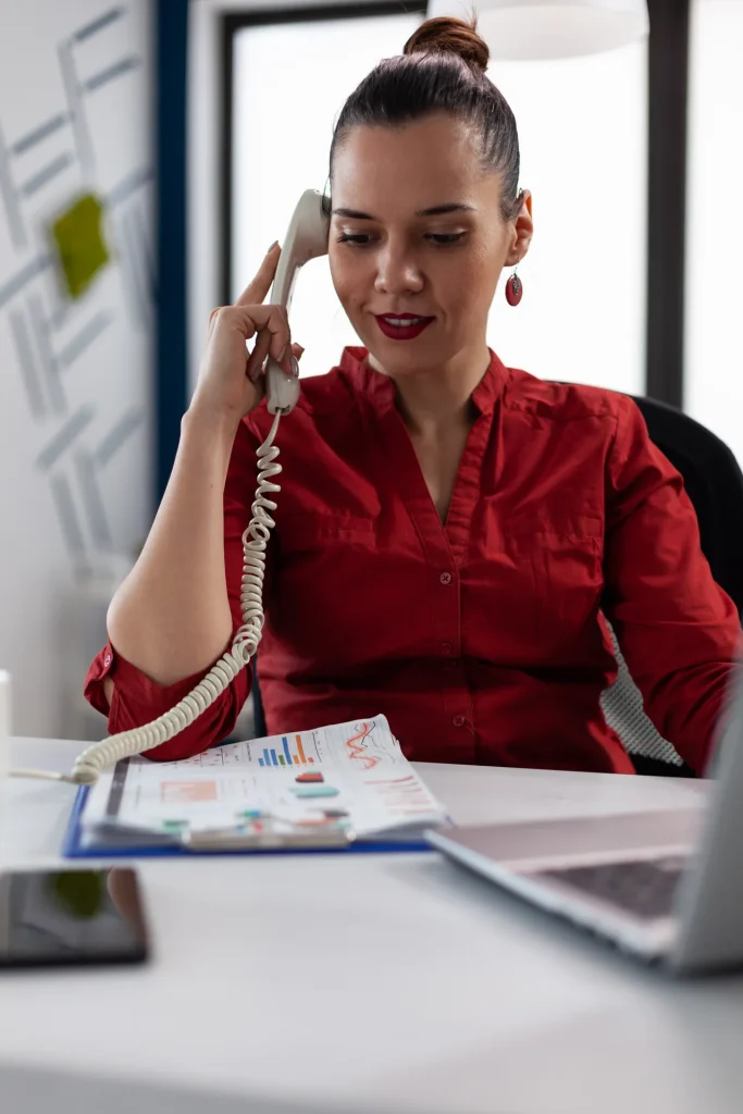 Profesional atendiendo una llamada con teléfono fijo en su mesa de trabajo
