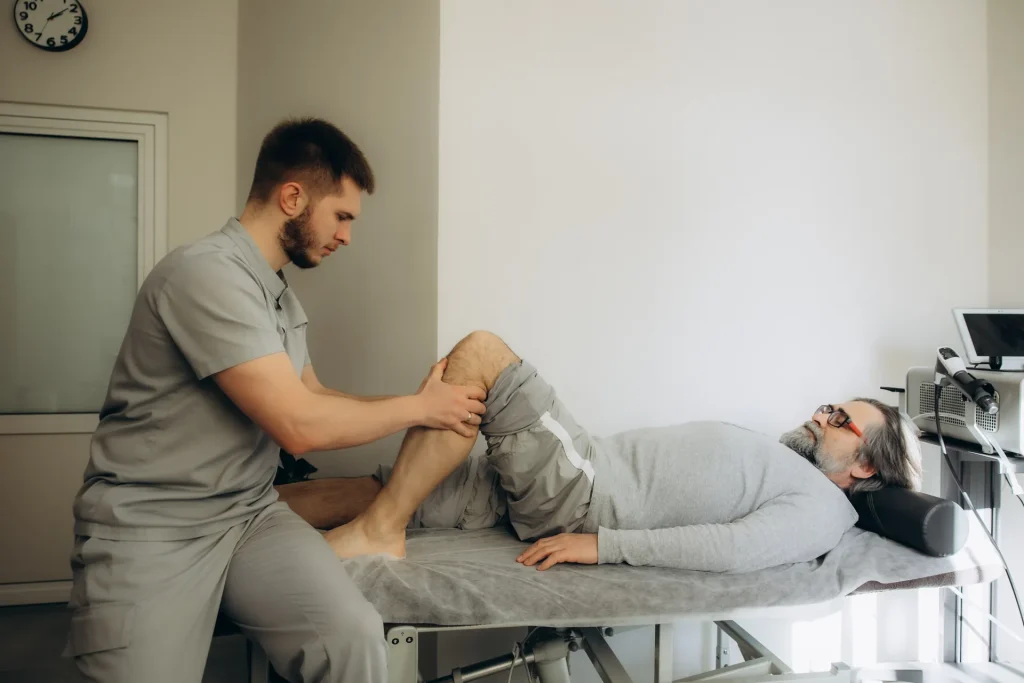Fisioterapeuta tratando la rodilla de un paciente mayor en la camilla