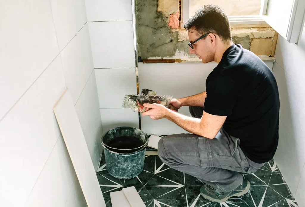 Operario colocando azulejos en un baño en reforma