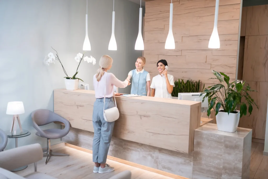 Recepcionistas atendiendo a una clienta en el mostrador de una clínica