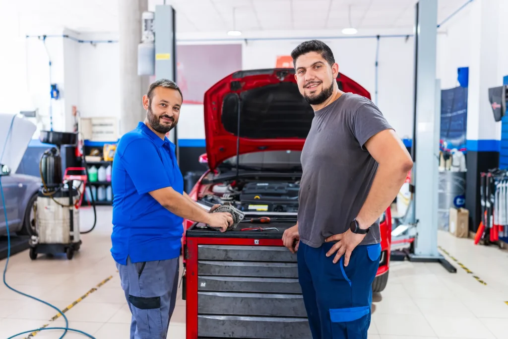 Dos mecánicos sonrientes junto a un coche en el taller