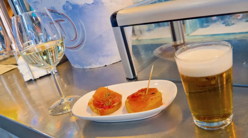 Copa de vino, caña de cerveza y tapas sobre la barra de un bar