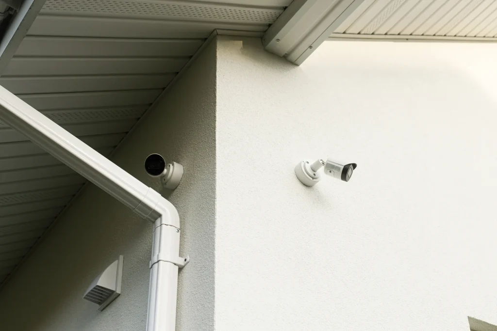 Dos cámaras de vigilancia en la fachada blanca de un edificio residencial