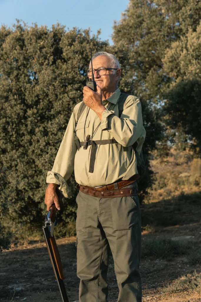 Guarda de una finca de caza coordinando la montería por walkie con la escopeta en la mano